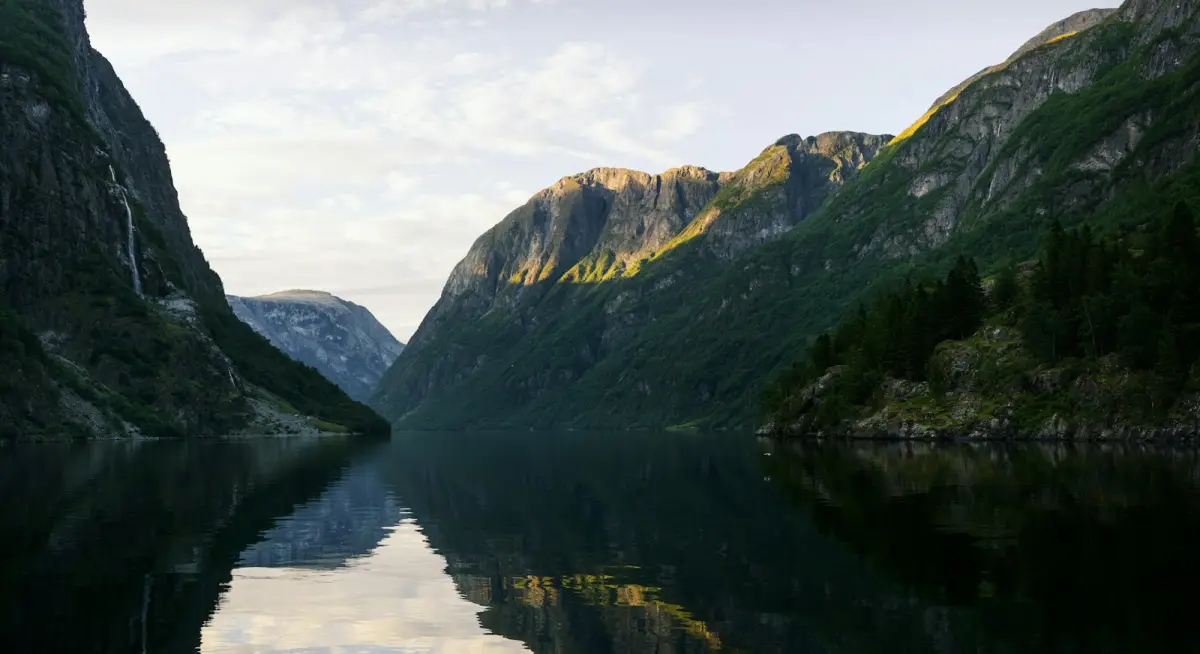 Green mountains reflected in a calm fjord in Geiranger, Norway