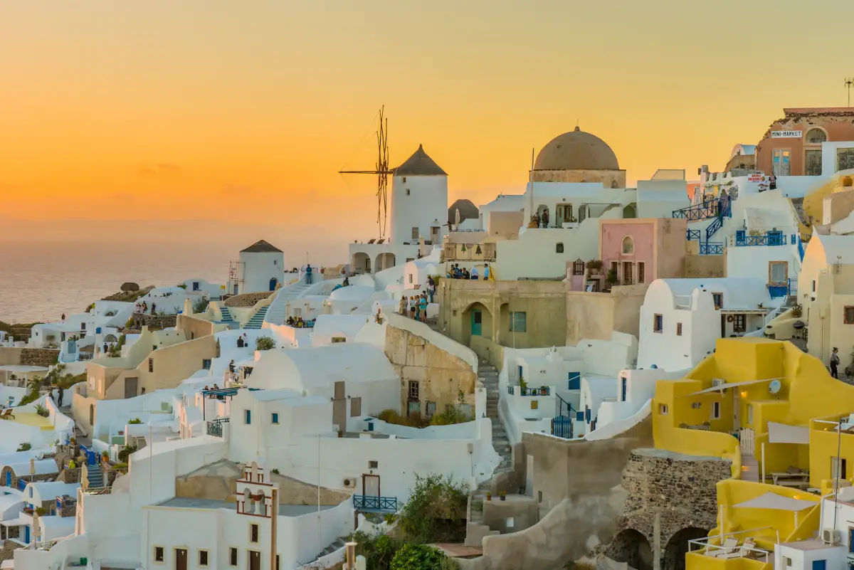 Whitewashed Santorini village and windmills above the Aegean Sea at sunset